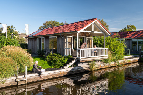 Senioren ontspannen bij een lodge aan het water met rood dak in Meine, Tusken de Marren, Nederland.