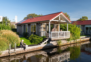 Senioren genießen ihre Zeit an einer Lodge am Wasser mit rotem Dach in Meine, Tusken de Marren, Niederlande.