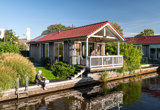 Senioren ontspannen bij een lodge aan het water met rood dak in Meine, Tusken de Marren, Nederland.