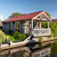 Seniors relaxing at a waterfront lodge with a red roof in Meine, Tusken de Marren, Netherlands.