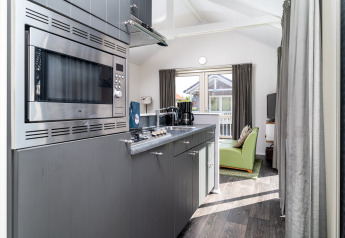 Moderne kitchenette in lodge Meine bij Tusken de Marren, Nederland, met grijze kasten en zitruimte.