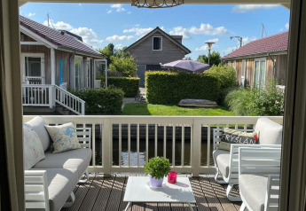 Lichte veranda van lodge Meine bij Tusken de Marren in Nederland, met zitbanken en zicht op de tuin.