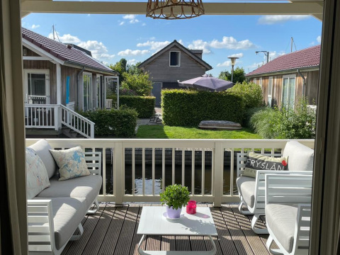 Lichte veranda van lodge Meine bij Tusken de Marren in Nederland met comfortabele banken en tuinzicht.