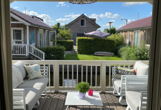 Lichte veranda van lodge Meine bij Tusken de Marren in Nederland met comfortabele banken en tuinzicht.