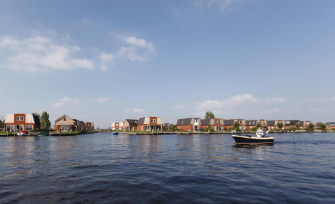Afbeelding van glampingverblijven aan het water, met een boot op de voorgrond en heldere lucht.