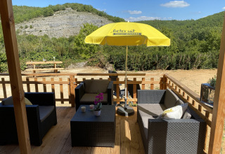Terraza de madera en la tienda de lujo Belle Vue en La Draille, Francia, con asientos y sombrilla amarilla.