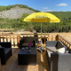 Træterrasse ved luksus safaritelten Belle Vue på La Draille, Frankrig, med havemøbler og parasol.
