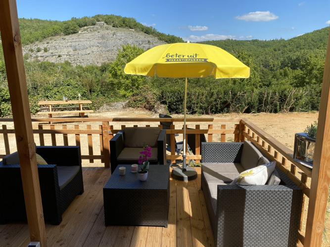 Houten terras bij luxe lodgetent Belle Vue op La Draille, Frankrijk, met loungeset en gele parasol.