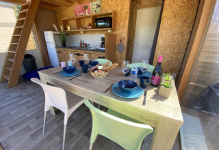 Essbereich und Küche in einem luxuriösen Safarizelt Belle Vue bei La Draille in Frankreich, vier Gedecke.