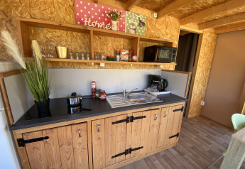 Coin cuisine d’une tente lodge de luxe Belle Vue à La Draille, France, avec placards et étagères en bois.