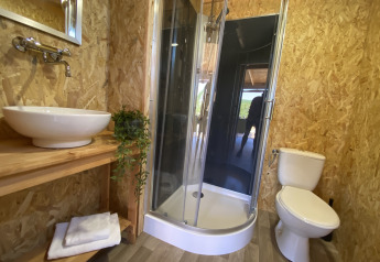 Badezimmer im Luxus-Safarizelt Belle Vue in La Draille, Frankreich, mit Dusche, Waschbecken und WC.