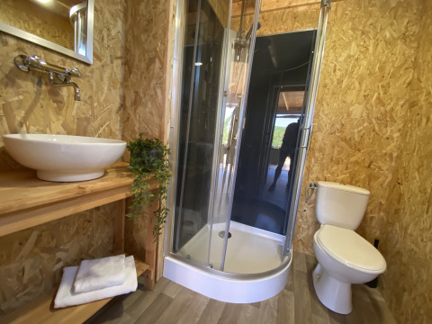 Badeværelse i luksus safaritelt på La Draille, Frankrig, med bruseniche, håndvask og toilet.