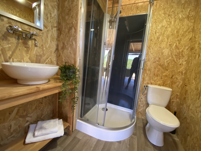 Baño en tienda de lujo Belle Vue en La Draille, Francia, con ducha, lavabo y aseo modernos.