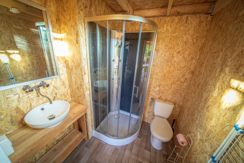 Salle de bain avec douche, lavabo et toilettes dans une tente safari de luxe à La Draille, France.
