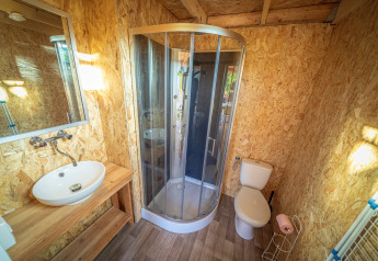 Badeværelse med brusekabine, håndvask og toilet i en luksuriøs safaritelt på La Draille, Frankrig.
