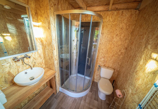 Bathroom with shower, sink and toilet in a luxury safari lodge tent at La Draille in France.