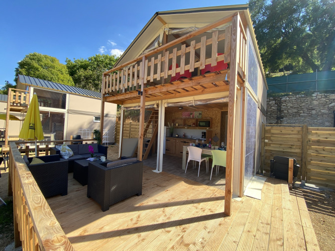 Tienda safari de lujo Belle Vue en La Draille, Francia, con terraza de madera y zona de estar al aire libre.