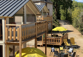 Espace extérieur du lodge de luxe Belle Vue à La Draille, France, avec terrasses ensoleillées et chaises jaunes.
