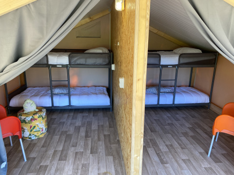 Interieur van de luxe safaritent Belle Vue bij La Draille in Frankrijk met stapelbedden en houten vloer.