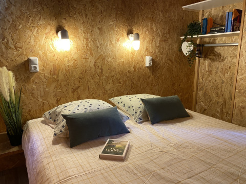 Intérieur cosy d'une tente lodge Belle Vue à La Draille, France, avec lit double et éclairages muraux.