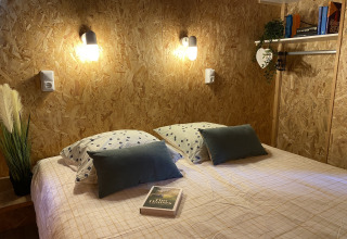 Gemütliches Schlafzimmer in einem Luxuszelt bei La Draille, Frankreich – Doppelbett und Wandlampen.
