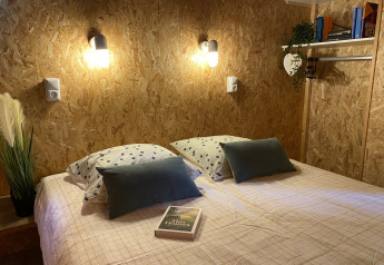 Sfeervol slaapkamerinterieur in de luxe safaritent Belle Vue bij La Draille, Frankrijk, met bed en lampen.