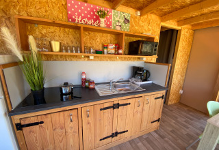 Keukengedeelte in de luxe lodgetent Belle Vue bij La Draille, Frankrijk, met houten kasten en planken.