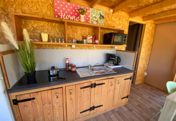 Keukenzone in de luxe lodgetent Belle Vue bij La Draille, Frankrijk, met houten kasten en rekken.