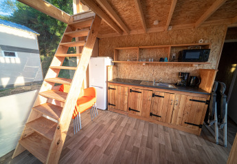 Binnenkant van een luxueuze lodgetent Belle Vue op La Draille in Frankrijk met keuken en houten trap.