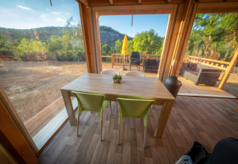 Zona de comedor dentro de la tienda Belle Vue en La Draille, Francia, con vistas a la naturaleza y terraza.