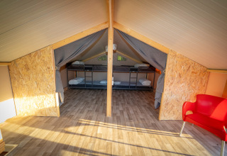 Intérieur de la tente lodge de luxe Belle Vue à La Draille, France, avec lits superposés et chaise rouge.
