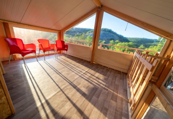 Heller Wohnbereich im Luxus-Safarizelt Belle Vue bei La Draille, Frankreich, mit roten Stühlen und Aussicht.