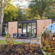 Veluwehoeve Wellness-lodge med udendørs spisested og rund hot tub omgivet af træer i naturen.