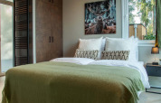Cozy bedroom at Veluwehoeve Wellness Lodge with a double bed, deer artwork, and sunlight from the window.