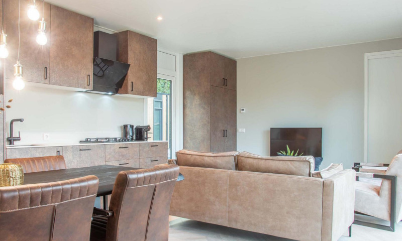 Lodge moderno con cocina abierta, comedor y sala de estar en Veluwehoeve Wellness (Hottub).