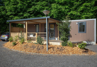 Cabaña familiar moderna en De Thijmse Berg, Países Bajos, con fachada de madera, porche y vegetación.