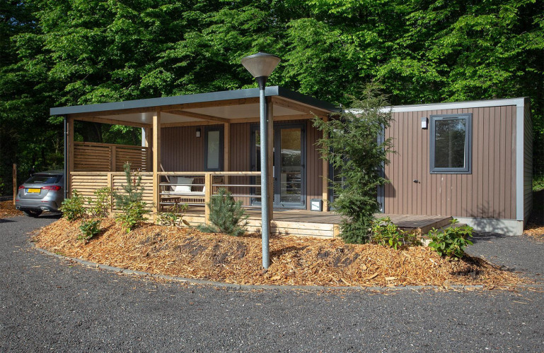 Cabaña familiar moderna en De Thijmse Berg, Países Bajos, con fachada de madera, porche y vegetación.