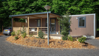Cabaña familiar moderna en De Thijmse Berg, Países Bajos, con fachada de madera, porche y vegetación.