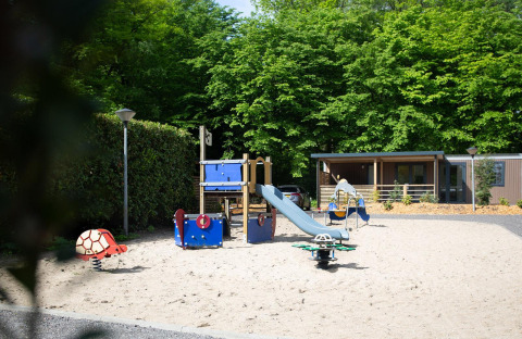 Área de juegos infantiles con tobogán frente a Family Cottage en De Thijmse Berg, Países Bajos.