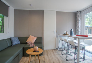 Moderne stue i Family Cottage på De Thijmse Berg, Holland, med hjørnesofa, spisebord og store vinduer.