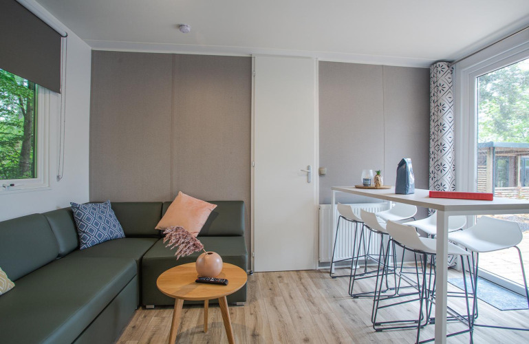 Modernes Wohnzimmer der Family Cottage bei De Thijmse Berg, Niederlande, mit Sofa, Tisch und großen Fenstern.