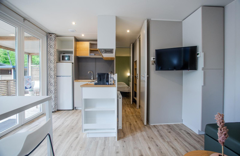 Modernes Familien-Cottage bei De Thijmse Berg in den Niederlanden mit Küche, TV und Blick ins Schlafzimmer.
