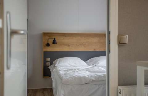 Vista de una cama con sábanas blancas en el Family Cottage de De Thijmse Berg, Países Bajos.
