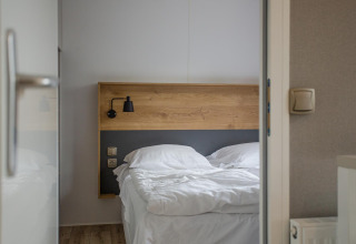 View of a bed with white linens in the Family Cottage at De Thijmse Berg, Netherlands.