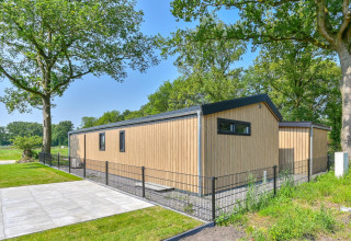 Moderne, rolstoeltoegankelijke houten lodge met omheining en groen bij Drentse Weelde, Nederland.