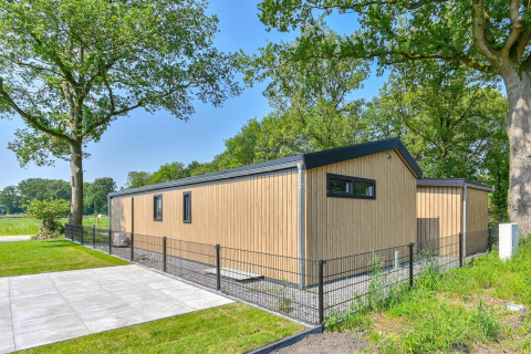 Moderne, rolstoeltoegankelijke houten lodge met omheining en groen bij Drentse Weelde, Nederland.