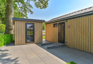Vista exterior de un lodge de lujo accesible para sillas de ruedas en Drentse Weelde, Países Bajos, rodeado de naturaleza.
