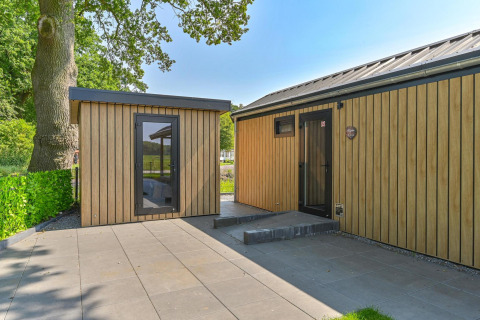 Außenansicht einer rollstuhlgerechten Luxus-Lodge bei Drentse Weelde in den Niederlanden, umgeben von Grün.