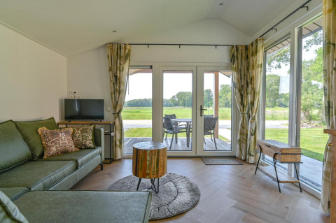 Soggiorno di una luxury lodge a Drentse Weelde, Paesi Bassi, con divano verde e vista sulla terrazza.
