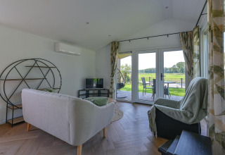 Living room in a luxury lodge at Drentse Weelde, Netherlands, with modern furnishings and scenic nature view.